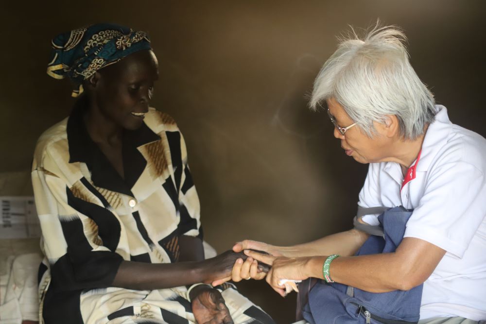 La Hna. Molly Lim, perteneciente a las Franciscanas Misioneras de María, reza con un refugiado sursudanés durante su visita al campo para predicar la paz y reconciliar a las comunidades, el 17 de febrero de 2023. (Fot: GSR/Doreen Ajiambo)