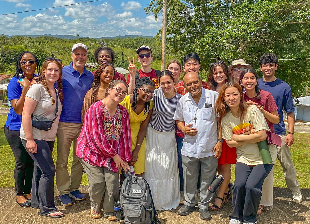 The group from the Boston College Volunteer and Service Learning Center gathers around Msgr. Gregory Ramkissoon (front row, second from right), the founder of Jamaica Mustard Seed, during the group's visit to Kingston, Jamaica. (Courtesy of Ana González)