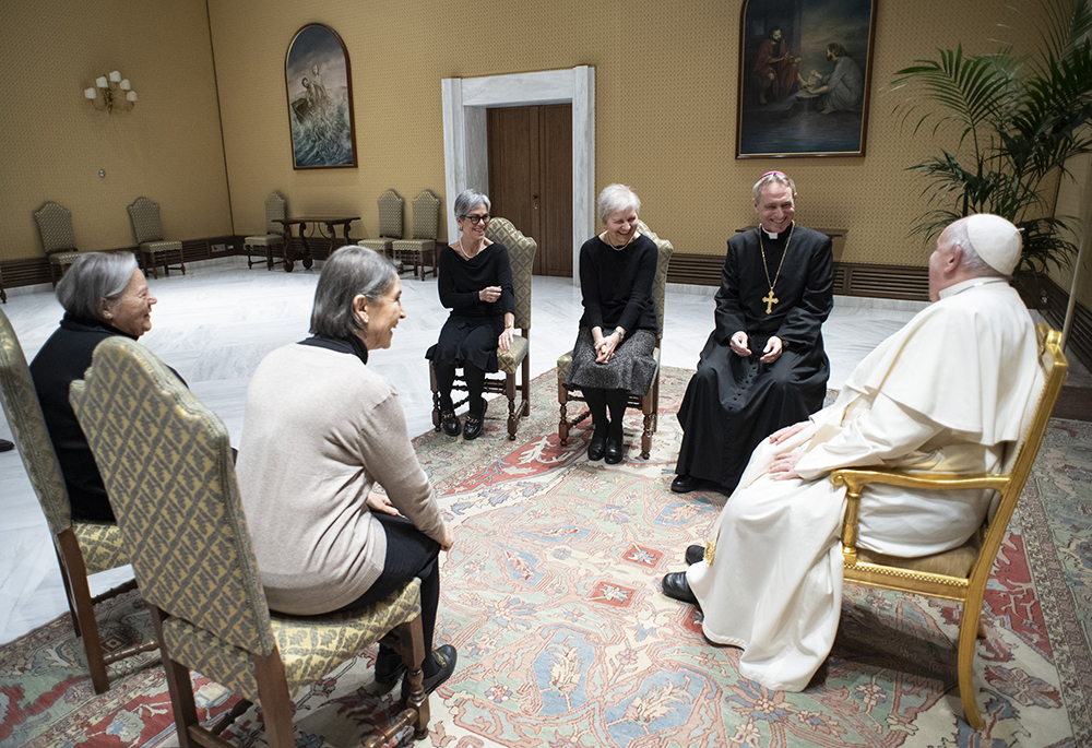 Pope Francis shares a laugh with Archbishop Georg Gänswein, secretary to the late Pope Benedict XVI, and with the consecrated women of Memores Domini who cared for the late pope and his household, during a meeting Jan. 3 at the Vatican. The first anniversary of Pope Benedict's death was Dec. 31. (CNS/Vatican Media)