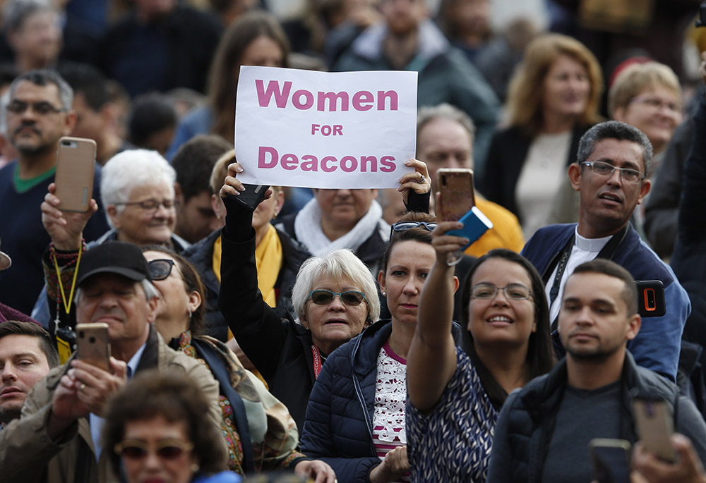 A woman holds a sign in support of women deacons as Pope Francis leads his general audience in St. Peter's Square Nov. 6, 2019, at the Vatican. (CNS/Paul Haring)
