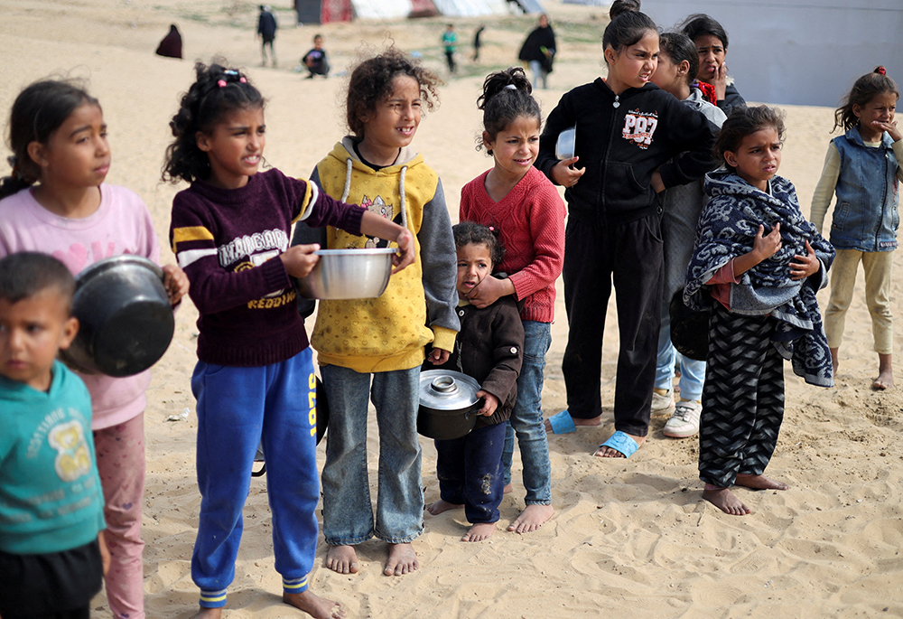 Displaced Palestinian children wait to receive free food at a tent camp, amid food shortages, as the conflict between Israel and Hamas continues, in Rafah in the southern Gaza Strip, Feb. 27. If Israel invades Rafah, the nearly 1 million displaced Palestinians there will have few or no safe places to go, a Catholic Relief Services official told NCR. (OSV News/Reuters/Ibraheem Abu Mustafa)