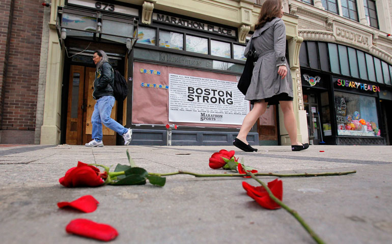 Flowers lie on the sidewalk at the site of the first Boston Marathon explosion as people walk along Boylston Street April 24. (CNS/Reuters/Jessica 