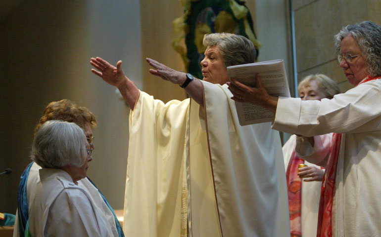 Rose Marie Dunn Hudson and Elsie Hainz McGrath kneel before Patricia Fresen, center, during a ceremony in November 2007 ordaining them as Roman Catholic Womenpriests in St. Louis. (CNS/Karen Elshout)