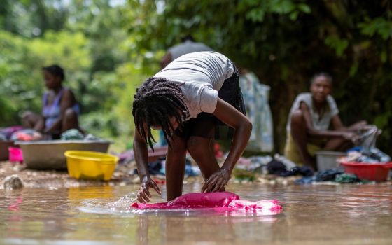 A woman washes clothes Aug. 22 in a river at a makeshift camp in Les Cayes, Haiti, for survivors of the Aug. 14 earthquake.