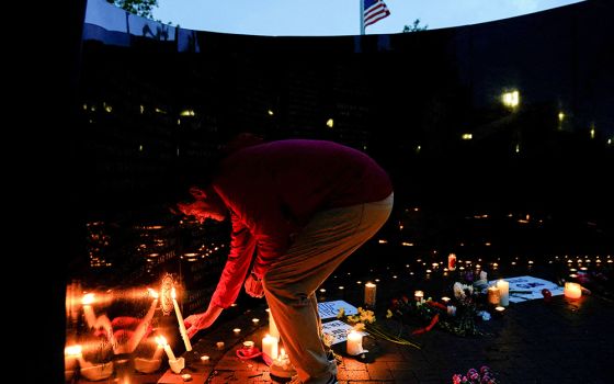 A person in the Chicago suburb of Highland Park, Illinois, lights a candle at a memorial site July 5 near the parade route the day after a mass shooting at a Fourth of July parade. Seven people were killed and dozens injured. (CNS/Reuters/Cheney Orr)