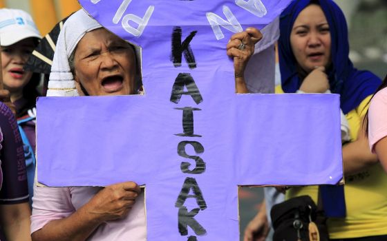 An activist holding a placard shouts anti-government slogans while protesting outside the presidential palace in Manila on March 8, 2016. In a statement on July 17, 2022, the religious superiors in the Philippines said "red-tagging" would not deter them f