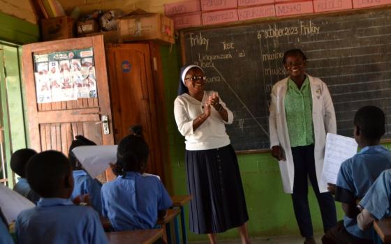 A nun and a teacher stand in front of a class. 