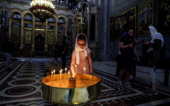 A girl places a candle in the Church of the Holy Sepulcher in Jerusalem's Old City on April 11, 2022. 
