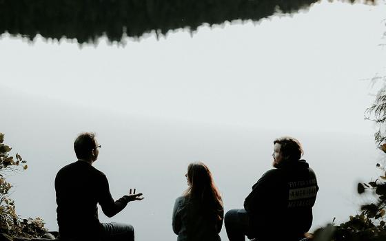 Silhouettes of three people in conversation (Unsplash/Priscilla du Preez)