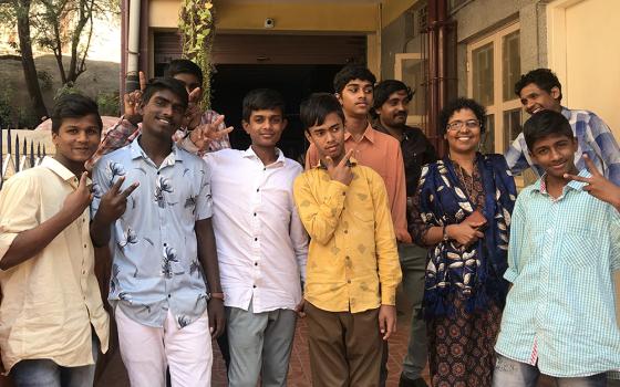 Anand and Ayyappan (far left) and their peers are pictured with Gleaners of the Church member Silvy Lawrence Pazherickal, in front of BOSCO Yuvakendra, a youth center for street children in Bengaluru, southern India. (Thomas Scaria)