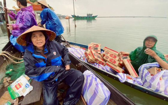 Lovers of the Holy Cross Sr. Mary Tran Thi Nhuong and volunteers carry instant noodles on boats to save flood victims in Quang Dien District. (Joachim Pham)