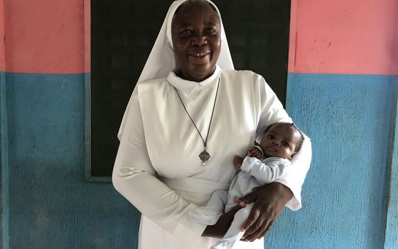 Sr. Matilda Inyang carries a child outside the Mother Charles Walker Children Home May 7 at the Handmaids of the Holy Child Jesus convent in Uyo, Nigeria. Since opening the home in 2007, Inyang has cared for dozens of children. (Valentine Iwenwanne)