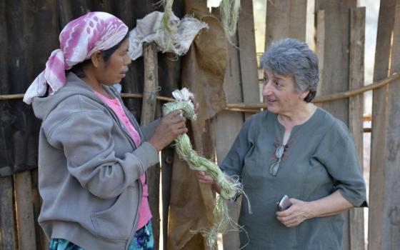 A Wichi indigenous woman, Griselda Arias, left, discusses natural fibers used for creating bags and jewelry with Sr. Norma Chiappe, at Arias' home in Lote 75, an indigenous neighborhood of Embarcacion, Argentina. (Paul Jeffrey)