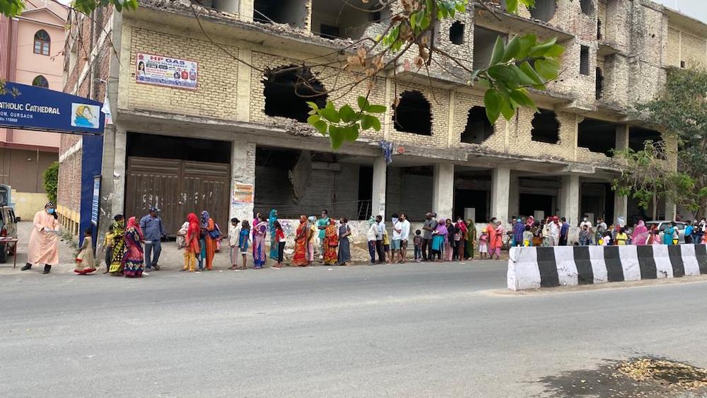 Bishop Jacob Mar Barnabas of the Gurgaon Syro-Malankara diocese, left, distributes food kits to those who have lined up in front of the cathedral during the coronavirus lockdown. (Courtesy of Fr. Nijo Kollentethekkethil)