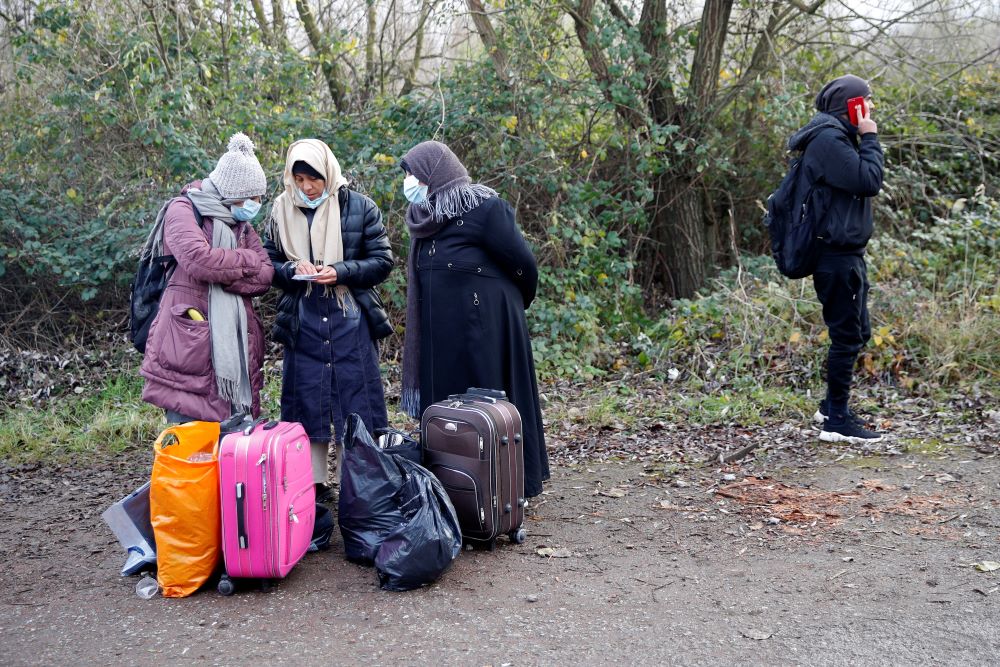 Migrants stand with their belongings at a makeshift migrant camp at Loon Beach in Dunkirk, France, Nov. 25, the day after 27 migrants died when their dinghy deflated as they attempted to cross the English Channel. (CNS/Reuters/Johanna Geron)