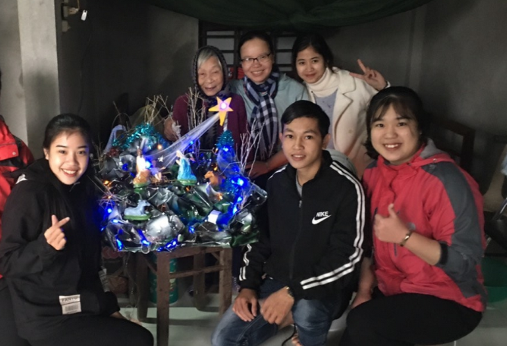 Daughters of Our Lady of the Visitation nuns and young Catholics offer a crèche to 84-year-old Anna Nguyen Thi Hoa at her house. (Joachim Pham)