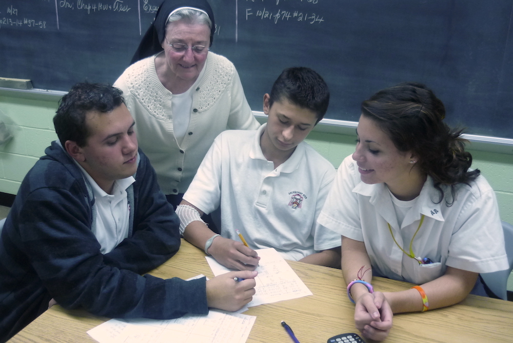 Sr. Alice Hess works with Archbishop Ryan High School students William Lightner, Sean Donnelly and Angilina DeTomasso in her classroom in the early 2000s. (Provided photo)