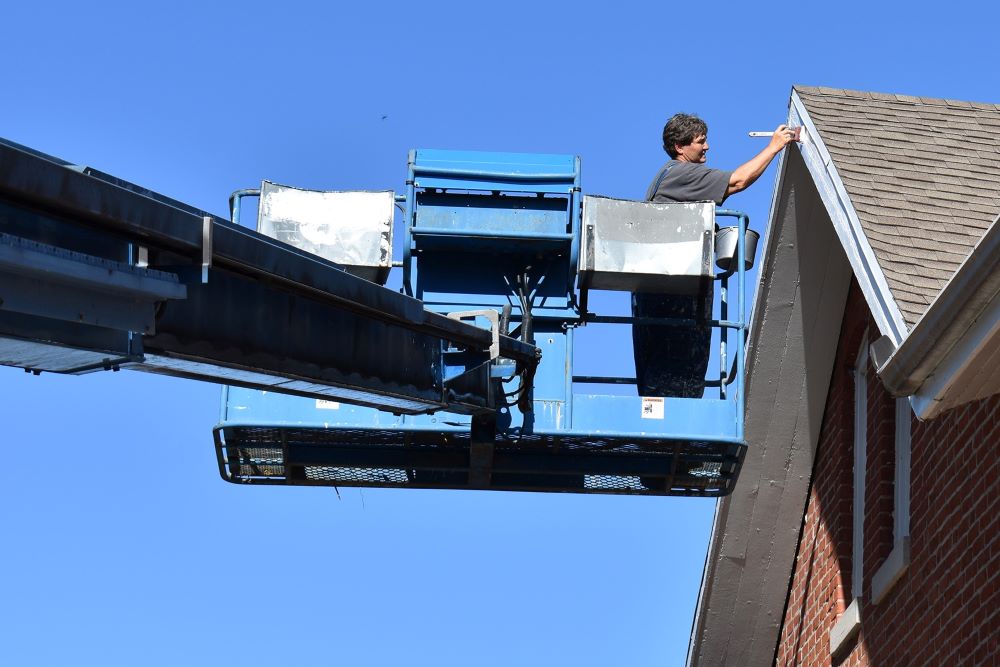 Benedictine Oblate Sr. Elaine Fischer is maintenance director at Mount St. Scholastica in Atchison, Kansas. She isn’t afraid of heights: Here she uses the lift reach the eaves of the maintenance shed for painting. (Julie A. Ferraro)