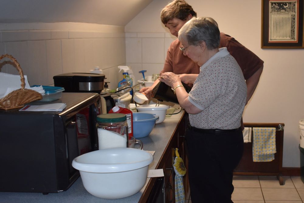 Sr. Elaine Fischer pours sugar into a mixing bowl as Sr. Irene Nowell prepares her father's eggnog recipe. (Julie A. Ferraro)