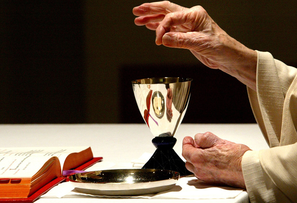 A Trappist priest mixes the consecrated bread and wine during Mass in a May 2006 file photo at Holy Cross Abbey in Berryville, Virginia. (CNS/Bob Roller)
