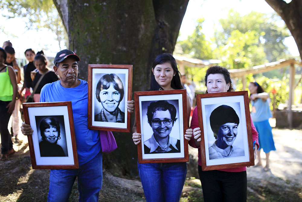 People hold pictures of four American churchwomen during a Dec. 2, 2015, memorial service. (CNS/Reuters/Jose Cabezas)