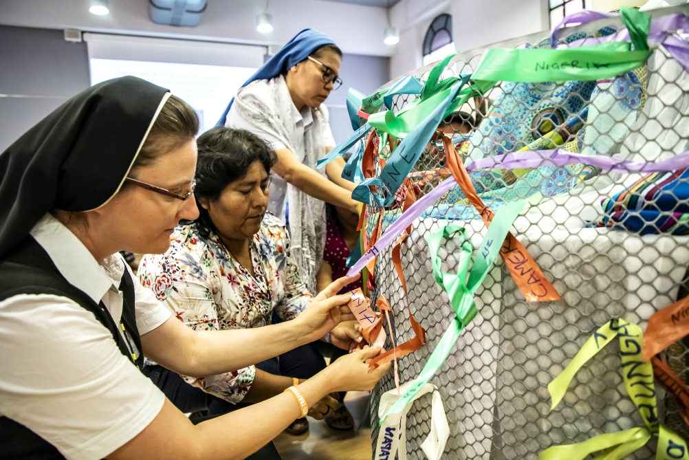 Sisters tie ribbons with the name of their country and a trafficking survivor with whom they have worked with Sept. 27 at the 10th anniversary gathering of Talitha Kum in Rome. (Courtesy of Talitha Kum)