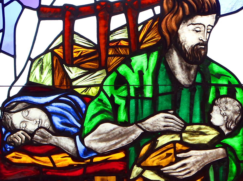 A depiction of St. Joseph cradling the infant Jesus while Mary sleeps is seen in a stained-glass window at St. Patrick Church in Smithtown, New York. (CNS/Gregory A. Shemitz)