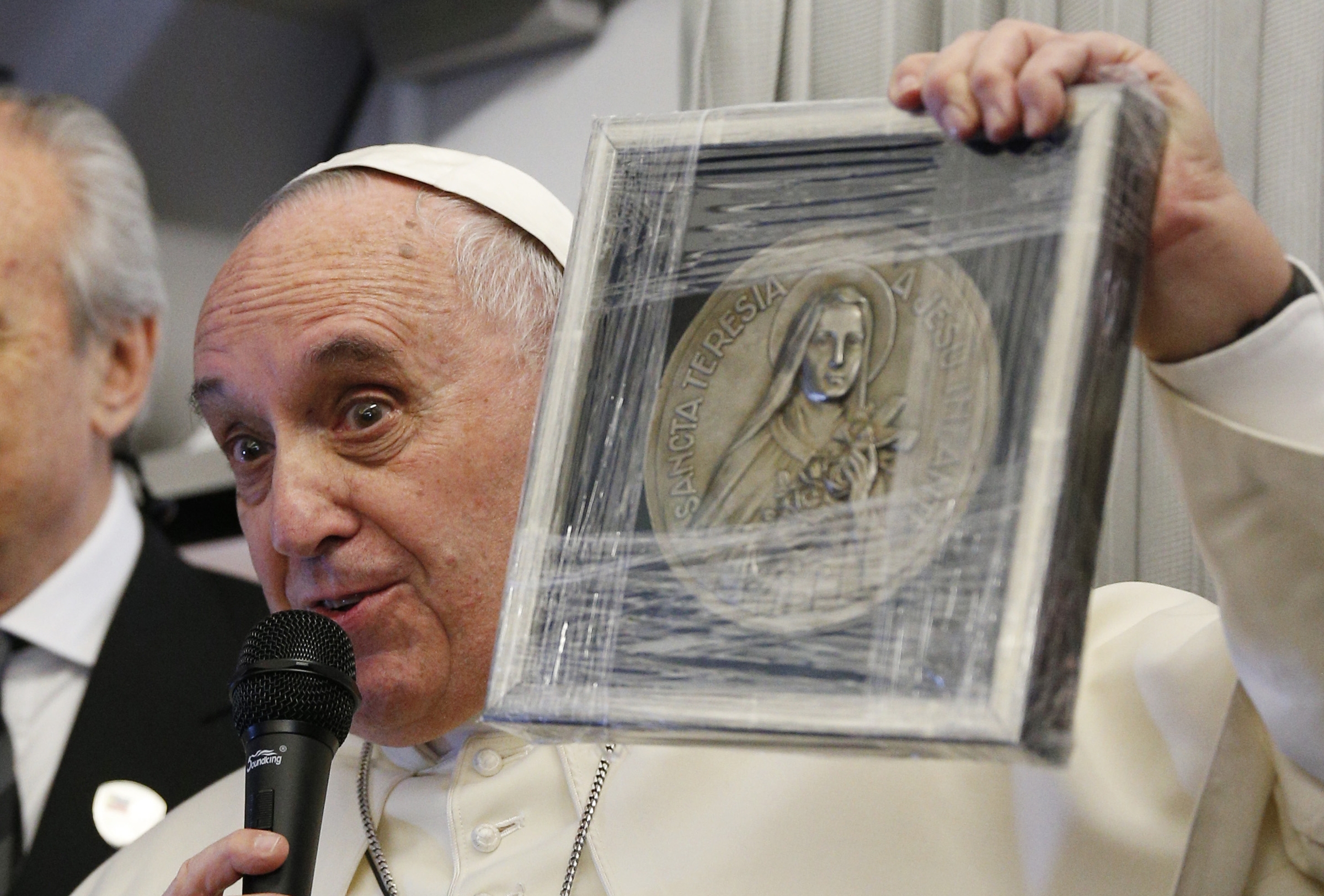 Pope Francis holds up a medallion of St. Therese of Lisieux aboard the papal plane Jan. 15, 2015. (CNS/Paul Haring)