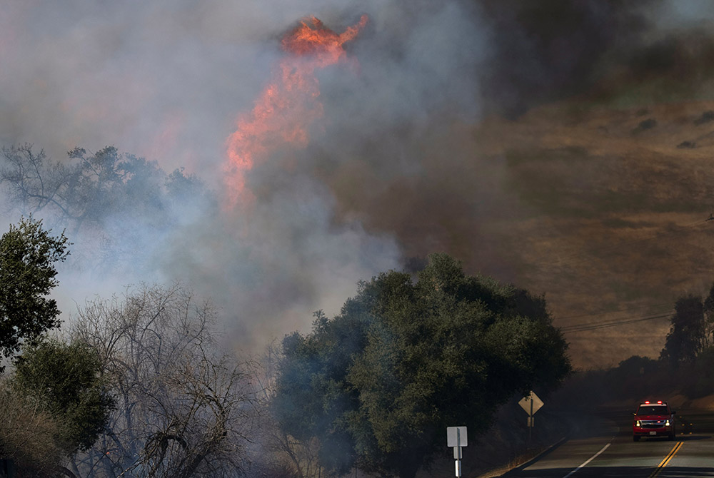 An emergency vehicle drives past the wind-driven Bond Fire wildfire near Lake Irvine, California, Dec. 3. (CNS/Mike Blake, Reuters)