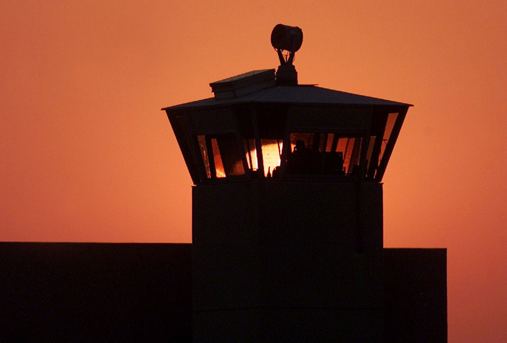 The sun sets behind one of the guard towers in a 2001 file photo at the Federal Correctional Complex in Terre Haute, Indiana, the site where the federal death penalty is carried out. (CNS/Reuters/Andy Clark)