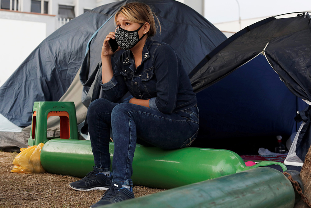Yoselin Marticorena, 26, talks on her cellphone March 3 while sitting outside a tent on the grounds of Hospital Villa El Salvador in Lima, Peru. (CNS/Reuters/Angela Ponce)