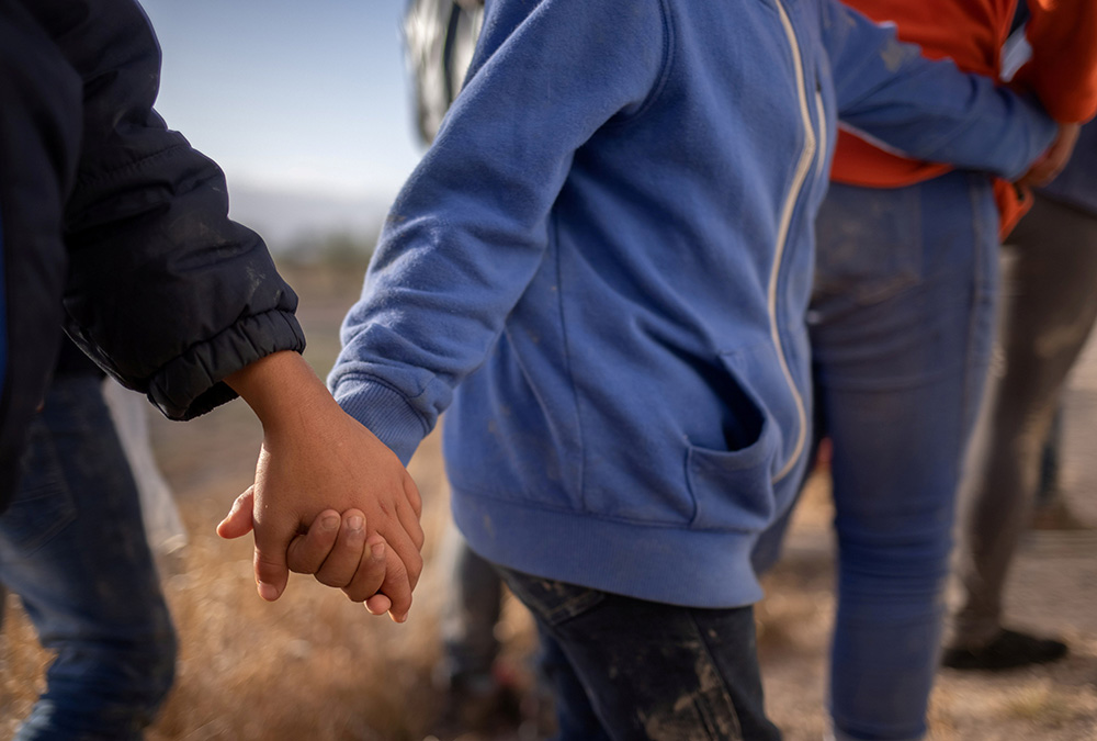 Unaccompanied minors from Central America seeking asylum in the United States hold hands March 12 as they await transport in Penitas, Texas, after crossing the Rio Grande. (CNS/Reuters/Adrees Latif) Unaccompanied minors from Central America seeking asylum in the United States hold hands March 12 as they await transport in Penitas, Texas, after crossing the Rio Grande. (CNS/Reuters/Adrees Latif)