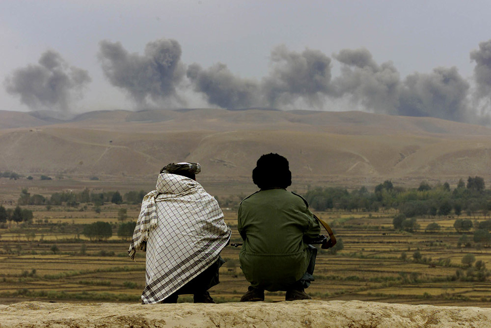 Two Northern Alliance soldiers near the village of Ai-Khanum in northern Afghanistan watch dust and smoke rise after explosions at Taliban positions Nov. 1, 2001. (CNS/Reuters/Vasily Fedosenko) Two Northern Alliance soldiers near the village of Ai-Khanum in northern Afghanistan watch dust and smoke rise after explosions at Taliban positions Nov. 1, 2001. (CNS/Reuters/Vasily Fedosenko)