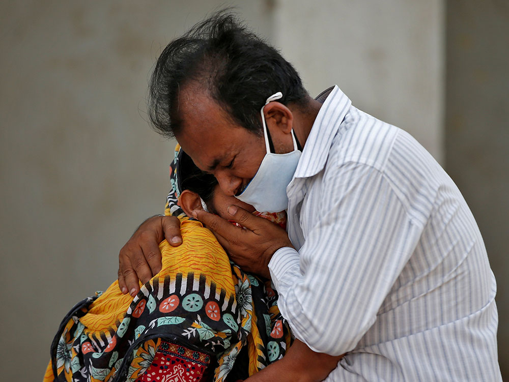 A woman cries in the arms of a relative April 26 outside a hospital in Ahmedabad, India, after her husband died from COVID-19 complications. (CNS/Reuters/Amit Dave)
