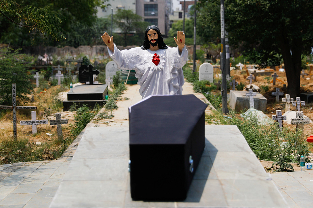 A statue of Jesus stands over the casket of a person who died after contracting COVID-19 before the burial at a graveyard in New Delhi on April 29, 2021. (CNS/Reuters/Adnan Abidi)