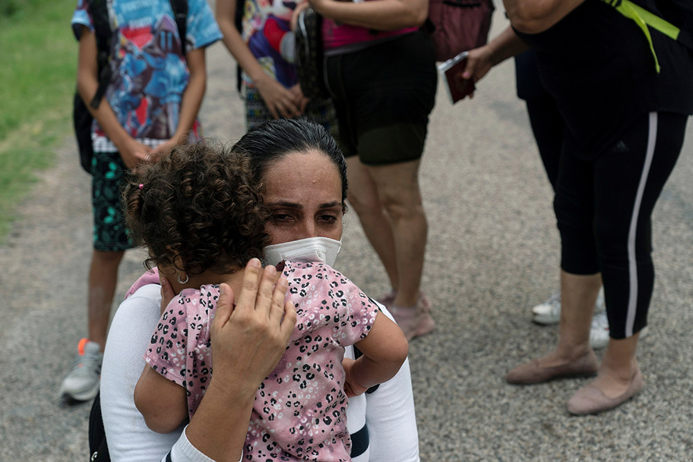 A migrant mother from Venezuela embraces her child as they wait to be transported by Border Patrol after crossing the Rio Grande into Del Rio, Texas, May 27, 2021. (CNS/Reuters/Go Nakamura)