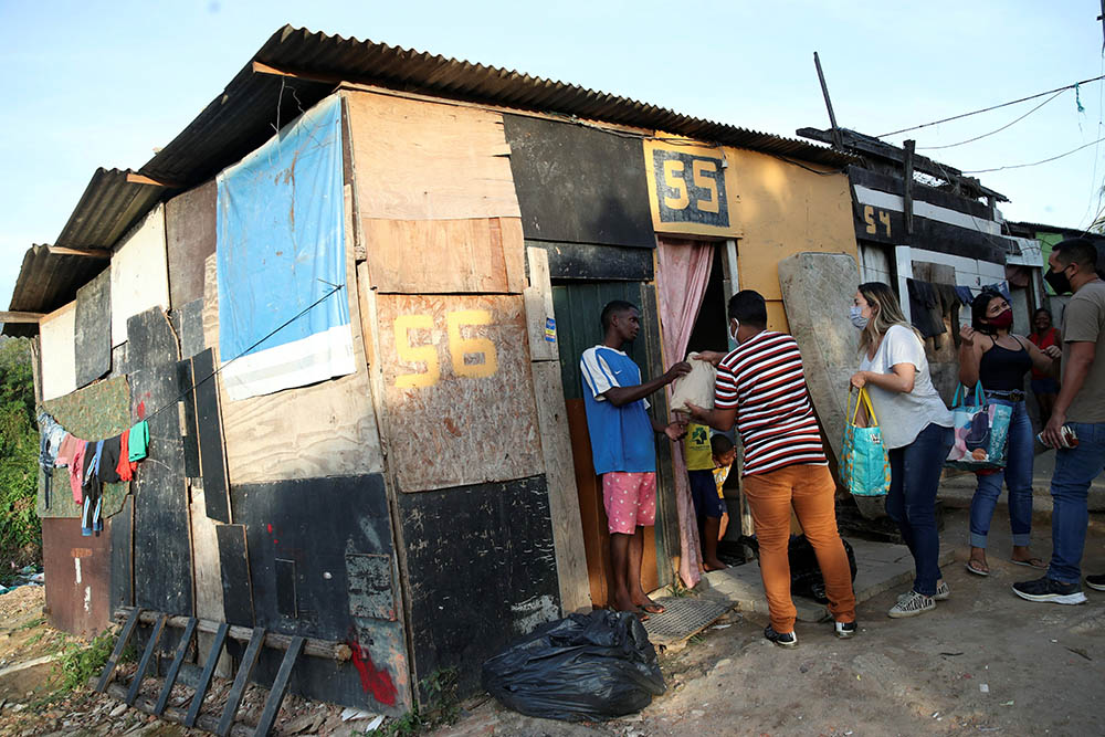 Residents in a poor section of Rio de Janeiro receive food and bread produced at the Sanctuary of Our Lady of Fatima during the COVID-19 pandemic. Volunteers delivered the bread June 24. (CNS/Reuters/Ricardo Moraes)