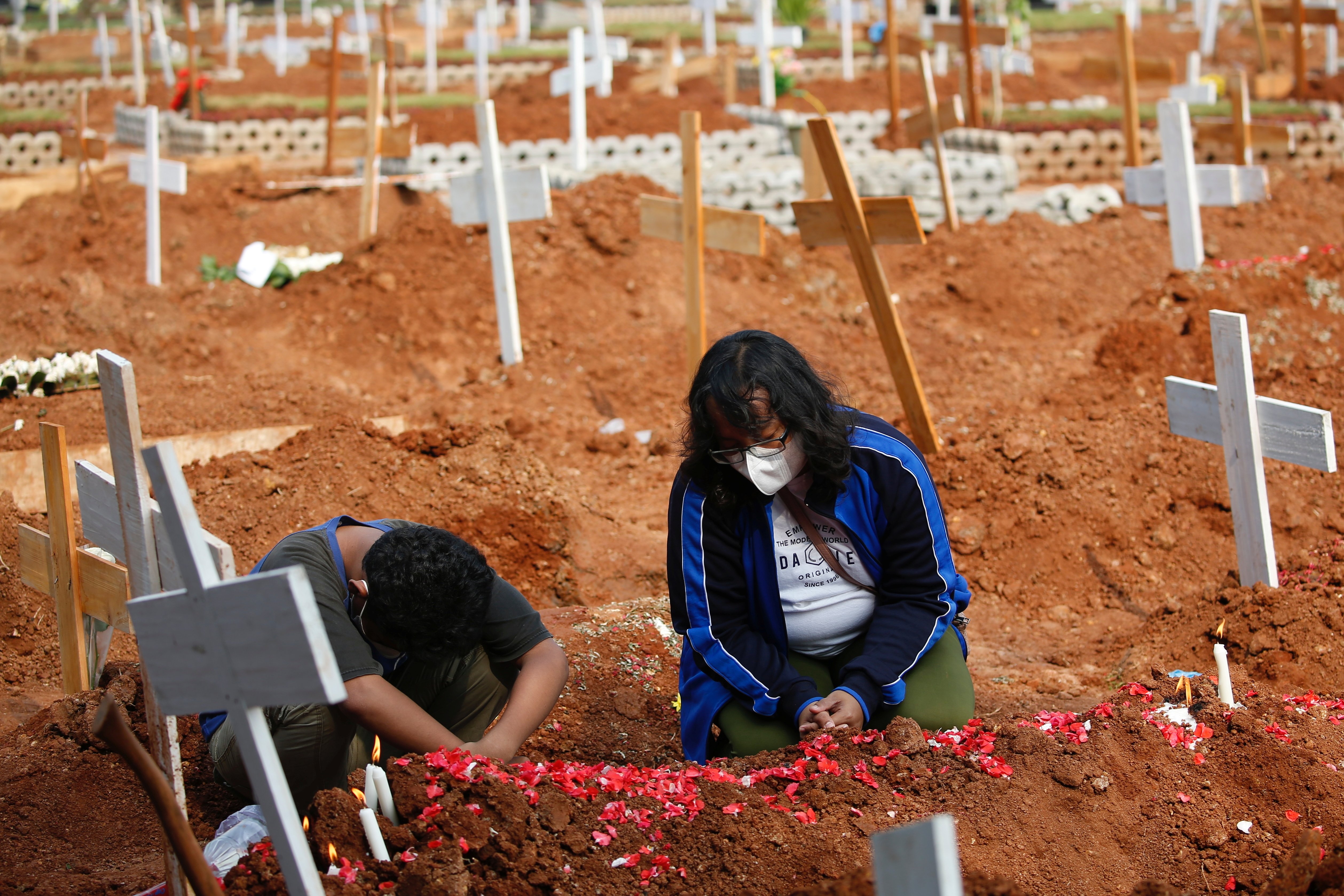 Indah Wulandari, 35, and her son, Nicolas Tegar, 12, pray July 15 at the grave of her husband at a government cemetery for COVID-19 victims in Bekasi, Indonesia. (CNS/Reuters/Willy Kurniawan)