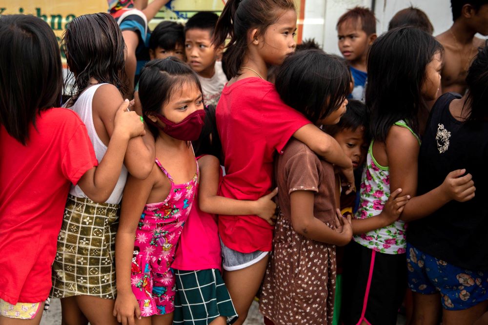 Children wait in line for free food from a relief program in a poor section of Manila, Philippines, on Jan. 21, during the COVID-19 pandemic. (CNS/Reuters/Eloisa Lopez)