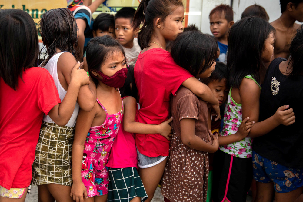 Children wait in line for free food from a relief program in a poor section of Manila, Philippines, Jan. 21. (CNS/Reuters/Eloisa Lopez)