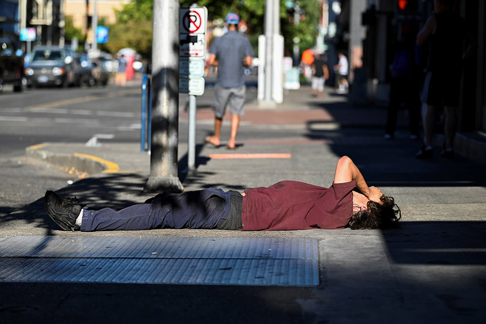A man in Portland, Oregon, lies on a sidewalk during a heat wave Aug. 11. (CNS/Reuters/Mathieu Lewis-Rolland)