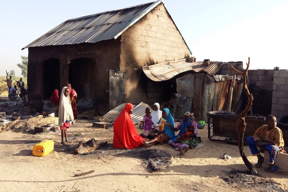 A family is pictured sitting near a damaged home after an attack by suspected members of the Islamist Boko Haram insurgency, Nov. 1, 2018, in Bulabulin, Nigeria. (CNS/Reuters/Kolawole Adewale)