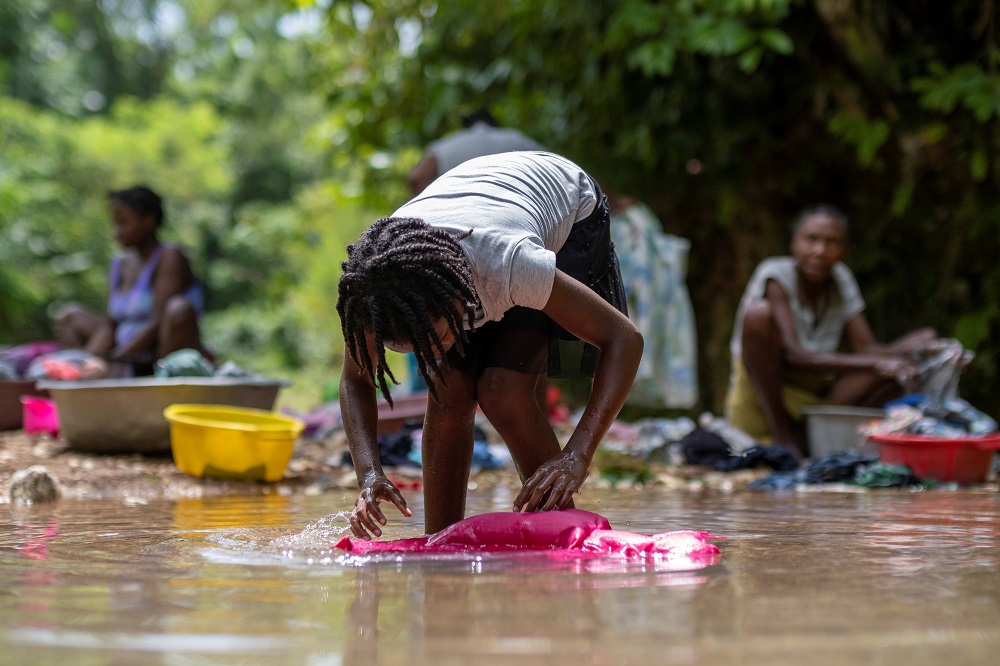 A woman washes clothes Aug. 22 in a river at a makeshift camp in Les Cayes, Haiti, for survivors of the Aug. 14 earthquake.