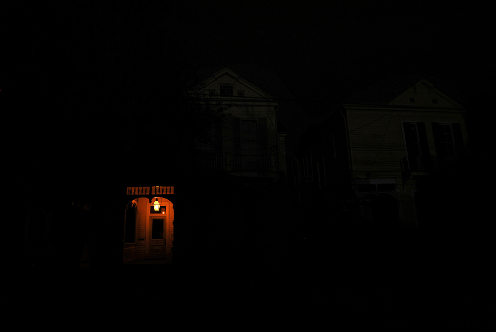 A front porch in New Orleans is lit by a flame on a dark street Aug. 31 in the midst of a power outage caused by Hurricane Ida. (CNS/Reuters/Leah Millis)