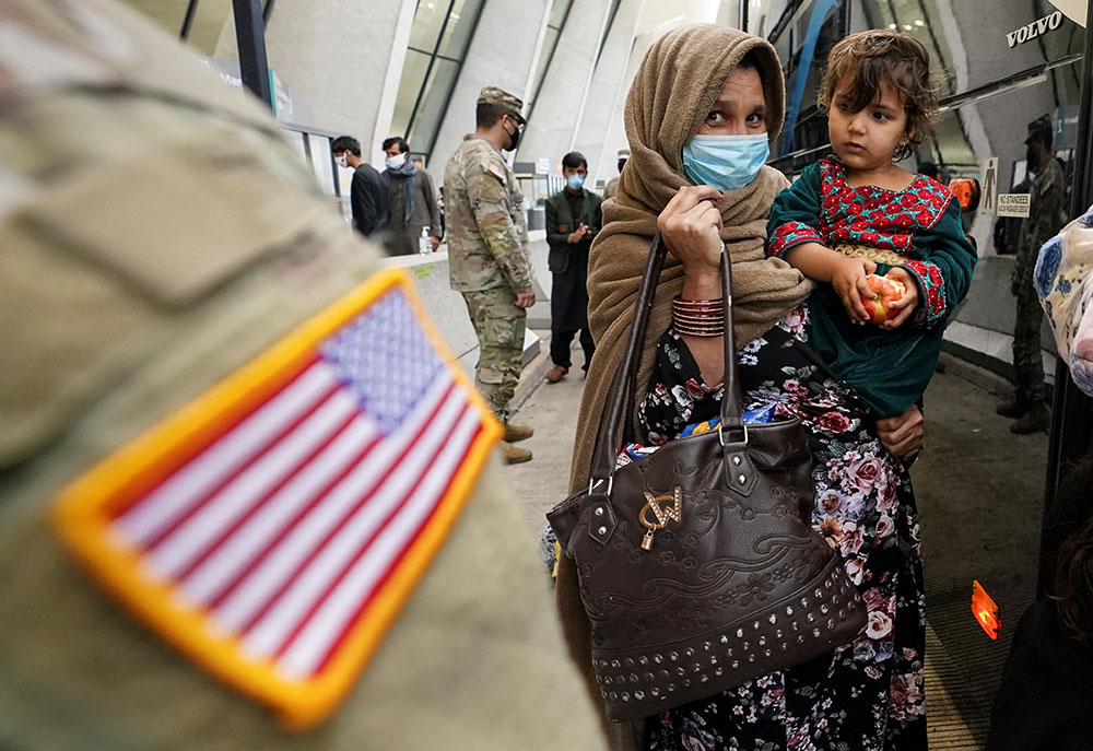 Upon their arrival, Afghan refugees board a bus at Dulles International Airport in Dulles, Virginia, Sept. 1, taking them to a processing center. (CNS/Reuters/Kevin Lamarque)