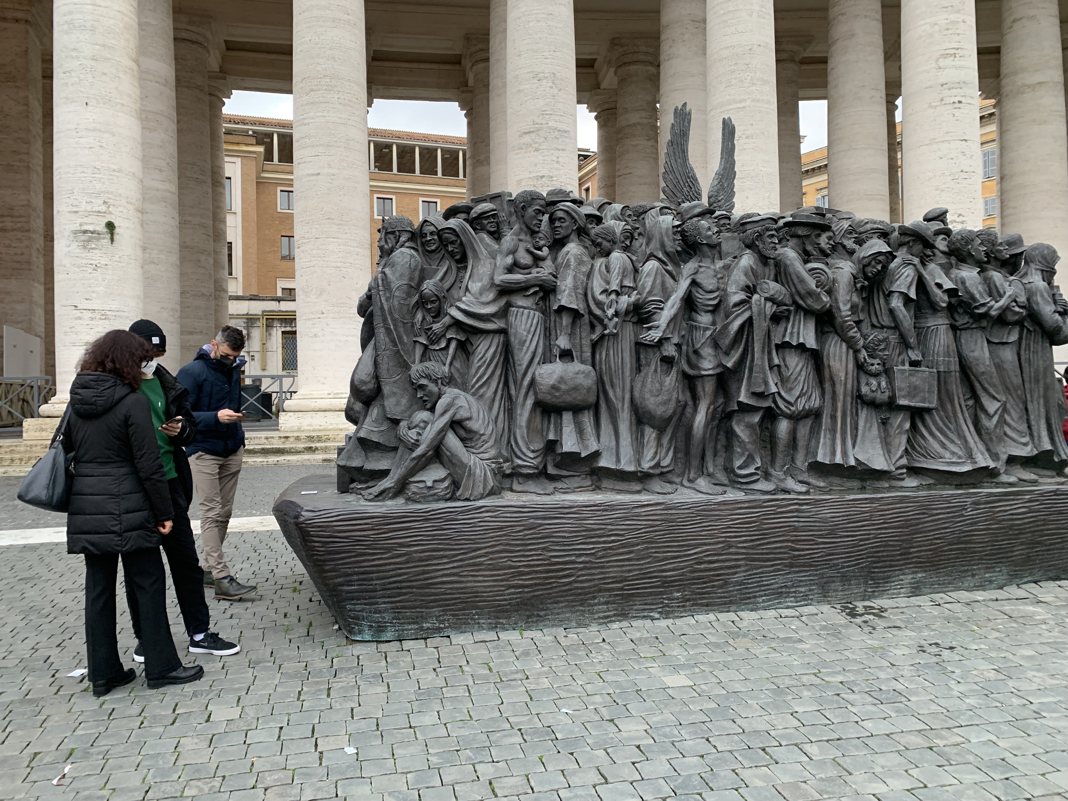 Visitors to St. Peter's Square use their smartphones to read about the sculpture "Angels Unawares" by Canadian sculptor Timothy Schmalz Dec. 28, 2021. (CNS photo/Cindy Wooden)