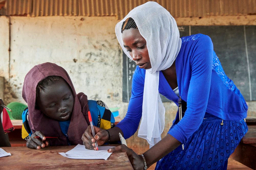 woman helps student at a desk