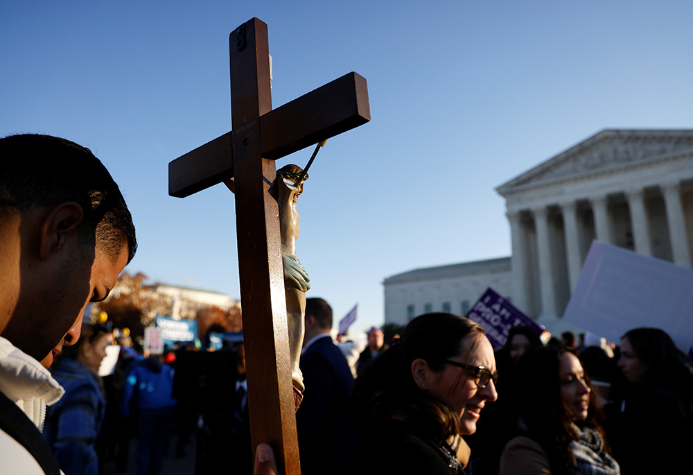 A pro-life activist holds a crucifix at a Dec. 1, 2021, protest outside the U.S. Supreme Court building in Washington, D.C. (CNS/Reuters/Jonathan Ernst)