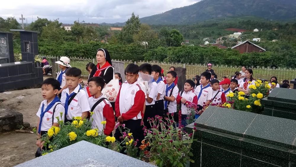 A nun takes children to the holy land, or cemetery, at Thai Xuan Parish in Xuan Loc Diocese to pray for the souls after Mass. (Photo courtesy of Mary Nguyen Lan)