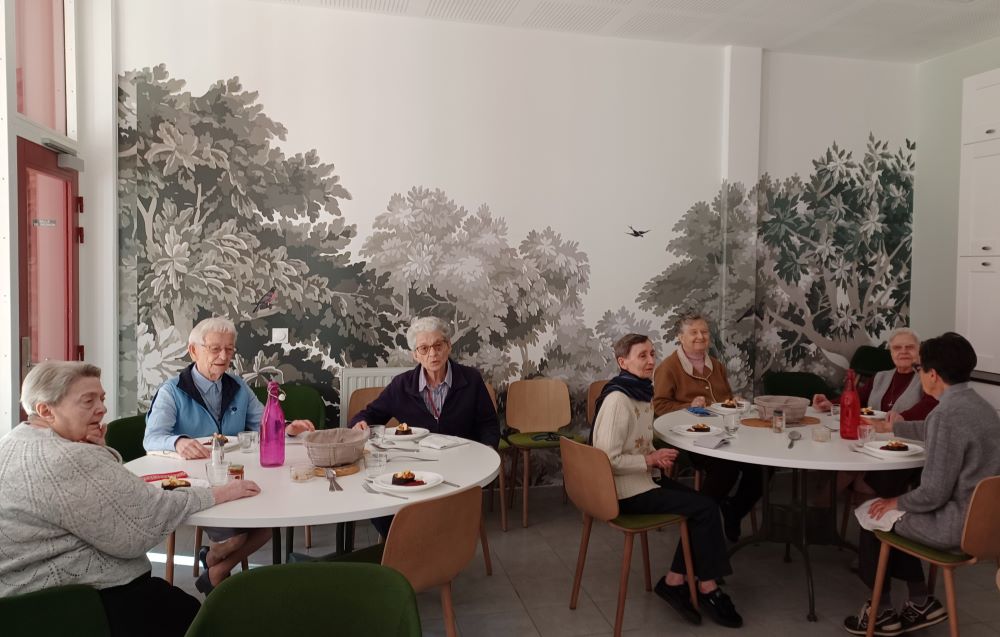 Sisters sit at two round tables during lunch. 